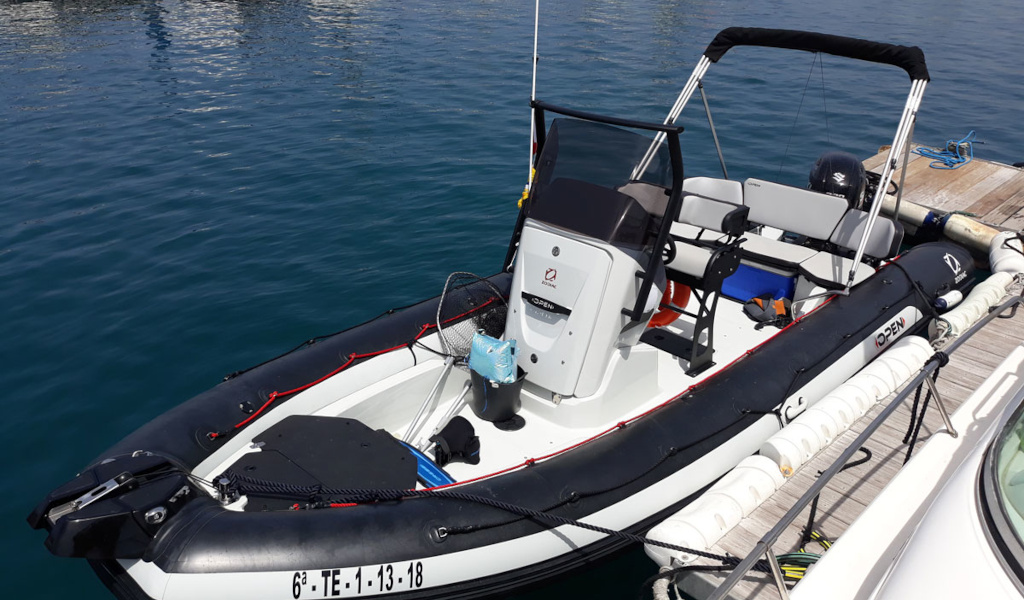 Een opblaasboot ligt aangemeerd in de haven van Tenerife, met zichtbare zitplaatsen en motor.