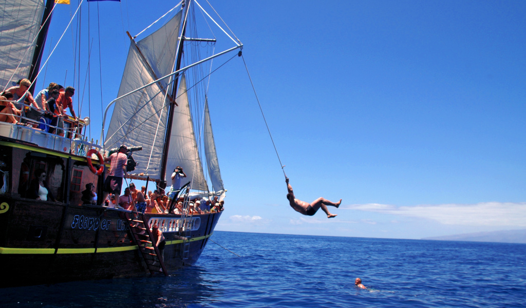 Iemand springt van een toeristenboot naar zee aan de kust van Tenerife.