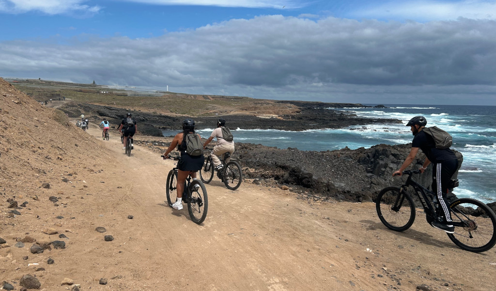 Fietsers die op een kustpad op Tenerife rijden aan zee en bewolkte luchten.