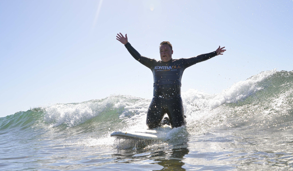 Surfer op golf met uitgestrekte armen, Kontraola t-shirt. Surfen op Tenerife.