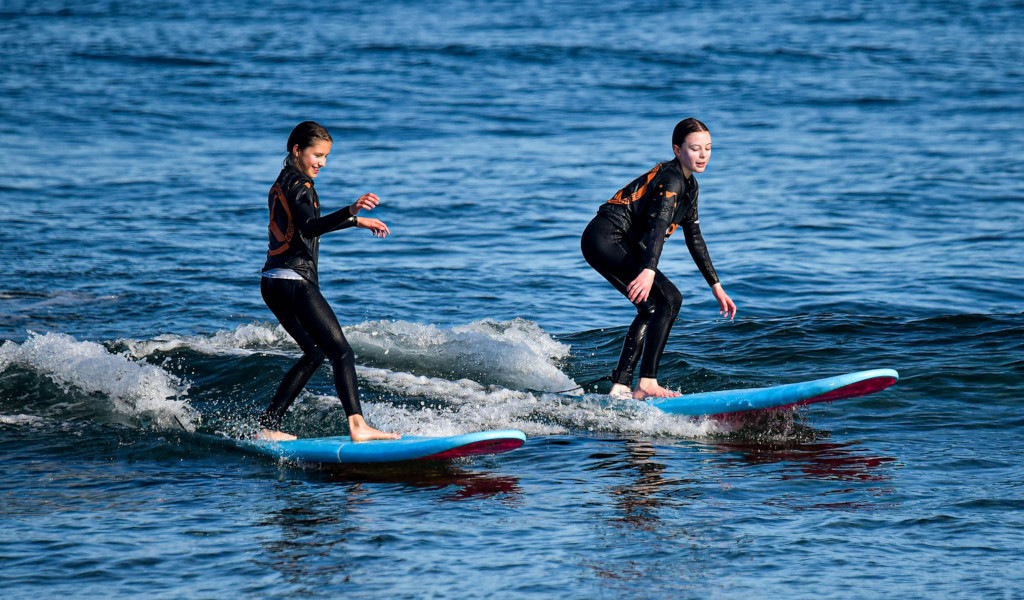 Twee mensen in wetsuits surfen op kleine golven in de zee van Tenerife.