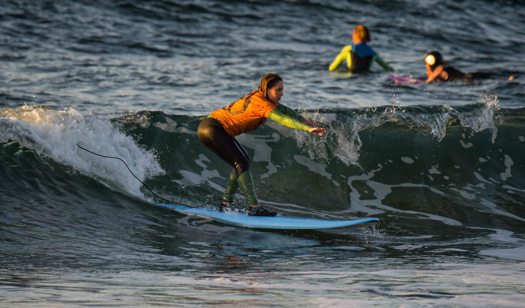 Surfer op het strand op Tenerife die op een golf rijdt bij zonsondergang.