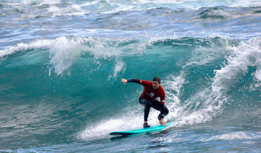 Surfer die op een golf surft op het strand op Tenerife.