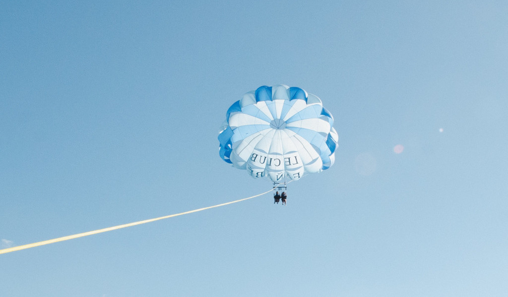 Parasailen boven de lucht van Tenerife met mensen onder witte en blauwe parachutes.