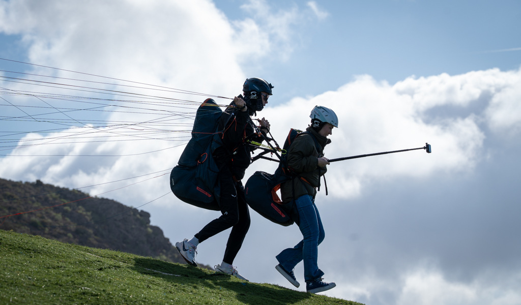 Twee mensen die opstijgen tijdens paragliding op Tenerife onder een bewolkte lucht.