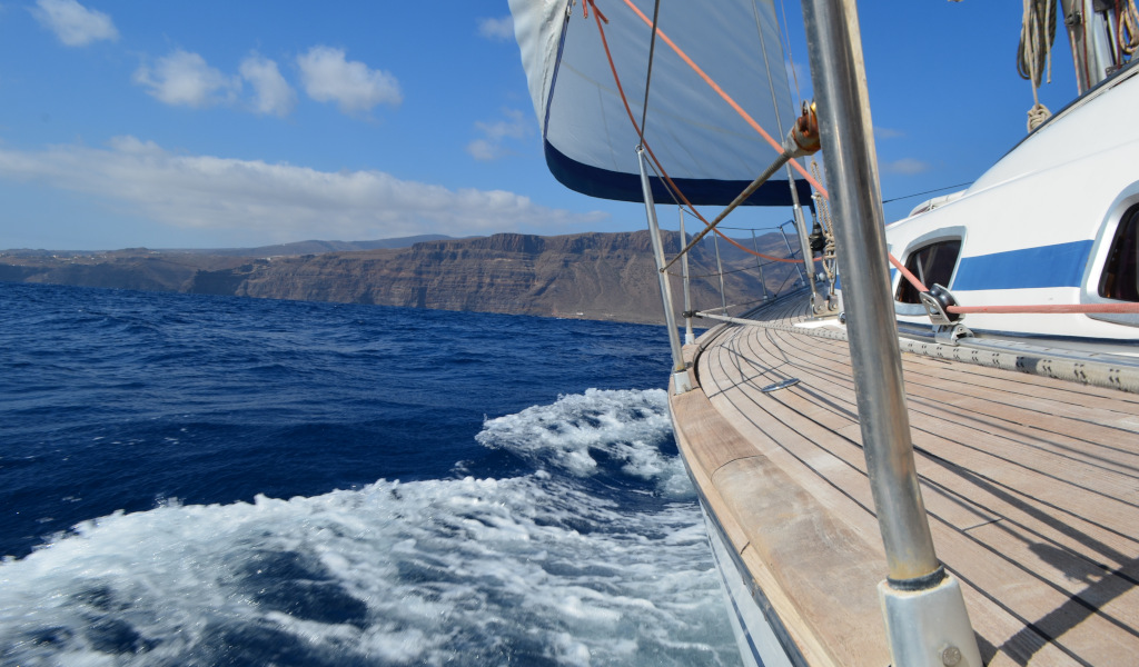 Zeilboot die langs de kust van Tenerife zeilt met bergen op de achtergrond.