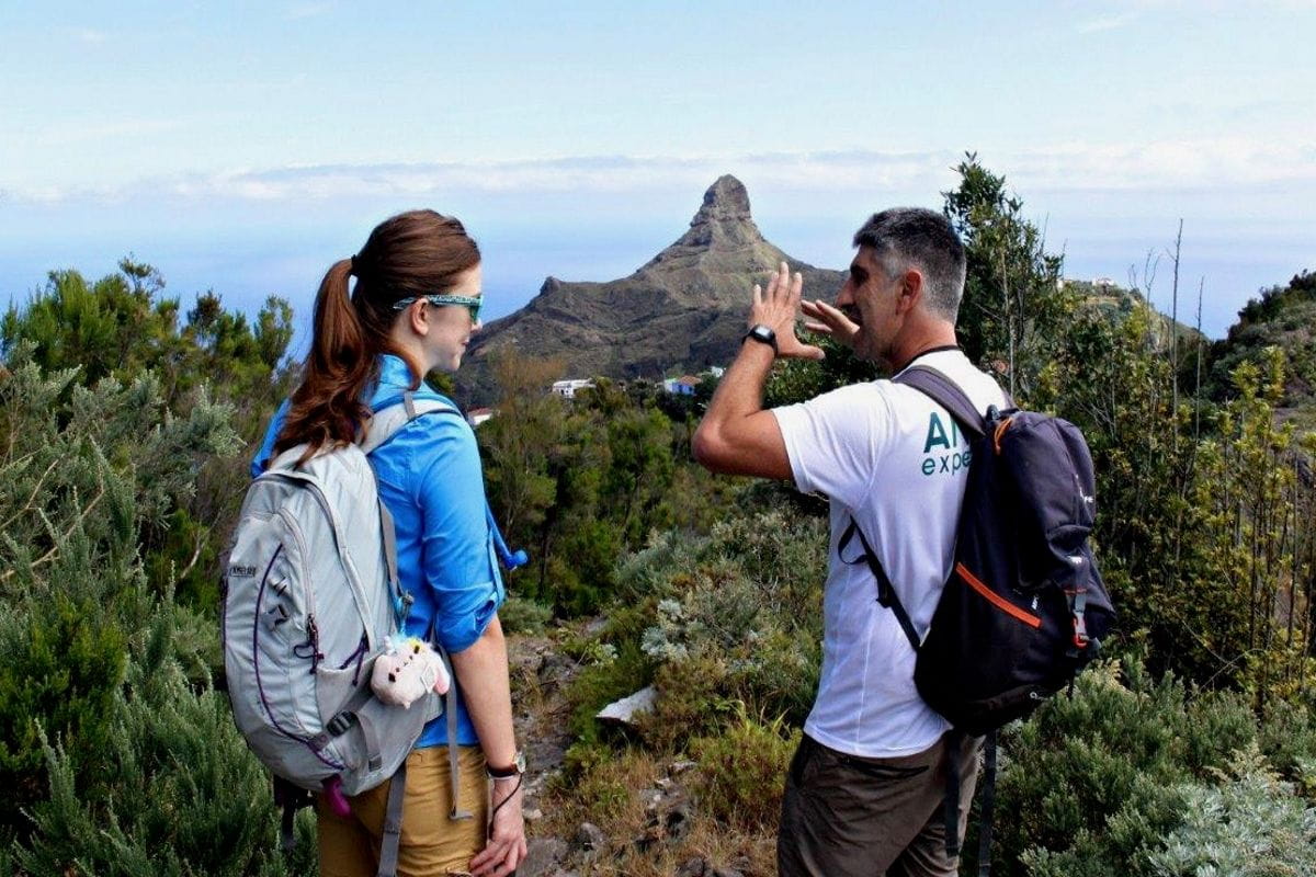 Twee mensen praten op een bergpad op Tenerife, met bergen op de achtergrond.