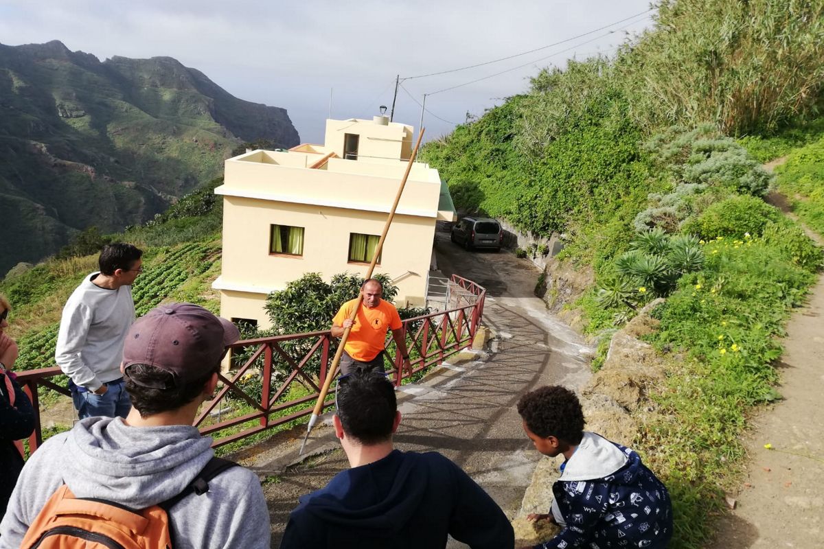 Mensen kijken naar een man met een stok op een weg in de bergen van Tenerife.