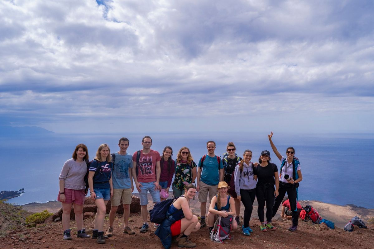 Groep mensen poseert bij een uitkijkpunt met uitzicht op de oceaan op Tenerife.
