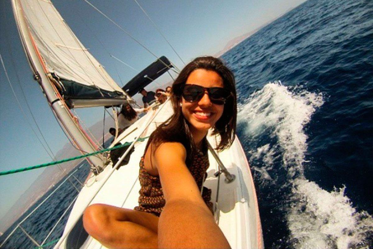 Persoon die glimlacht op een zeilboot die langs de kust van Tenerife vaart.