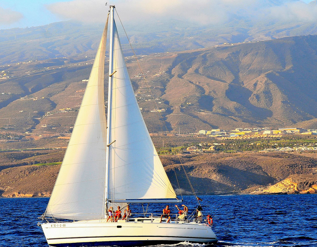 Zeilboot die langs de kust van Tenerife zeilt met bergen op de achtergrond.