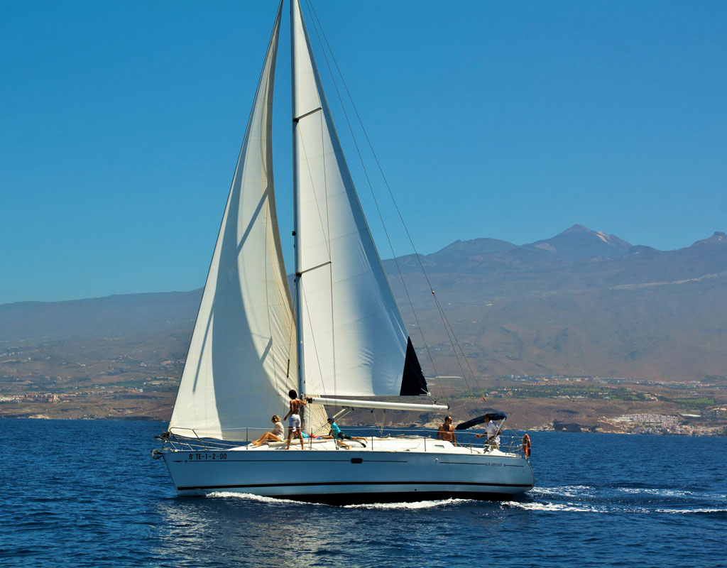Zeilboot die voor de kust van Tenerife zeilt met bergen op de achtergrond.