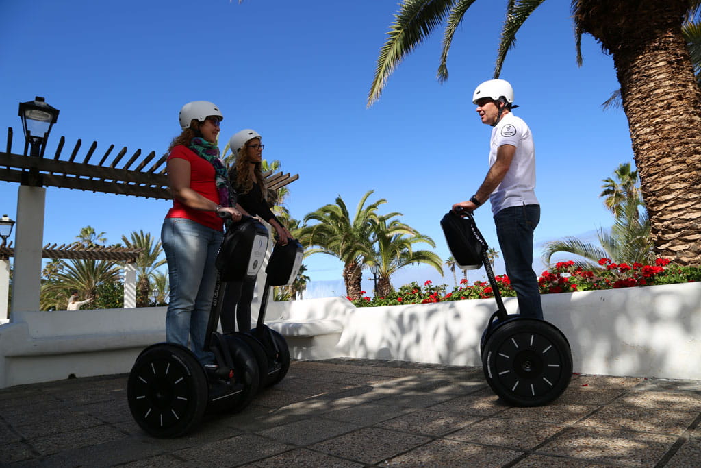 Mensen op segways die tussen palmbomen op Tenerife lopen.