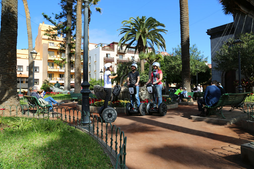 Mensen op segways rijden door een park met palmbomen in La Laguna, Tenerife.