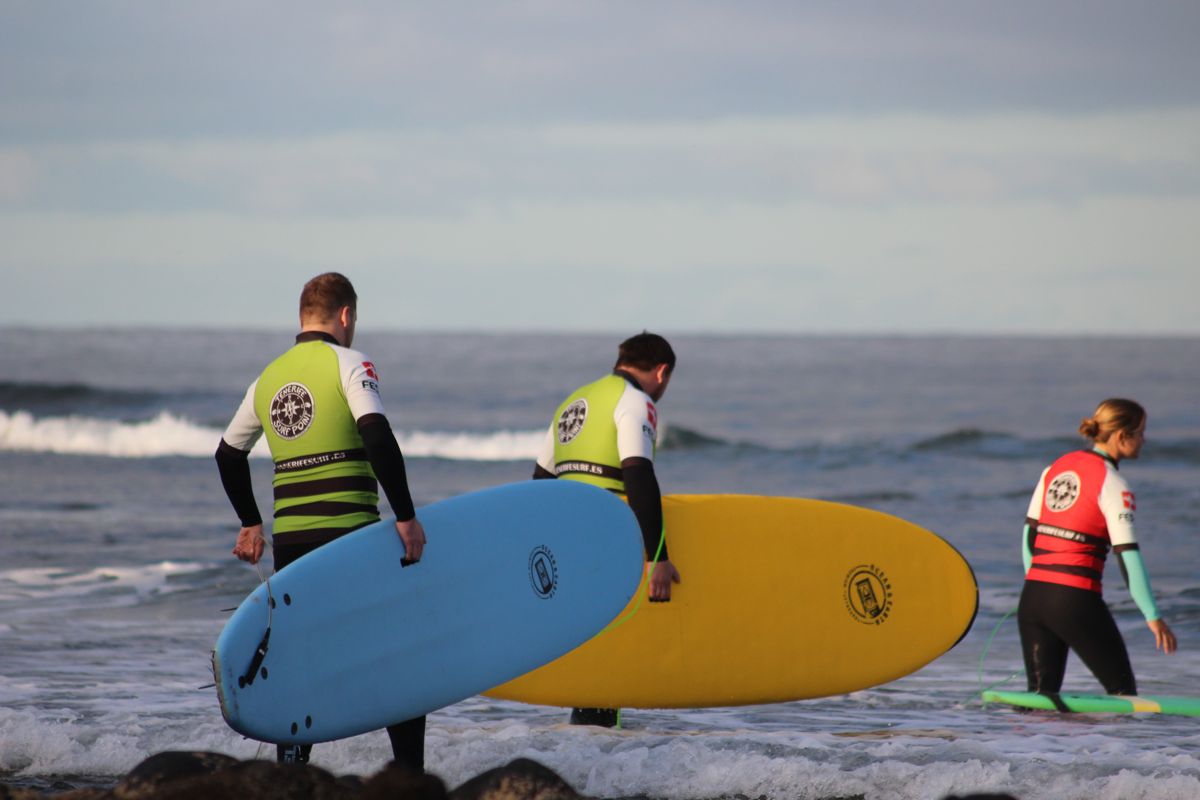 Surfers die de zee ingaan met kleurrijke boards op Tenerife.