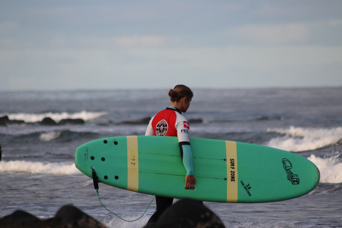 persoon met groene surfplank op het strand op Tenerife