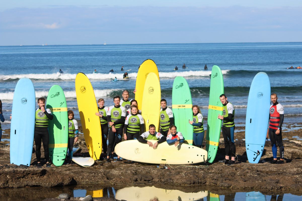 Groep surfers met gekleurde boards op het strand van Tenerife.