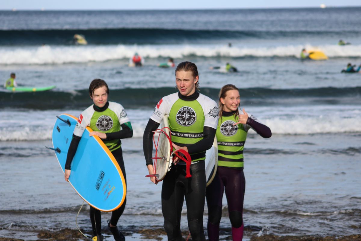 Surfers op het strand op Tenerife, met boards en wetsuits, vlak bij de zee.
