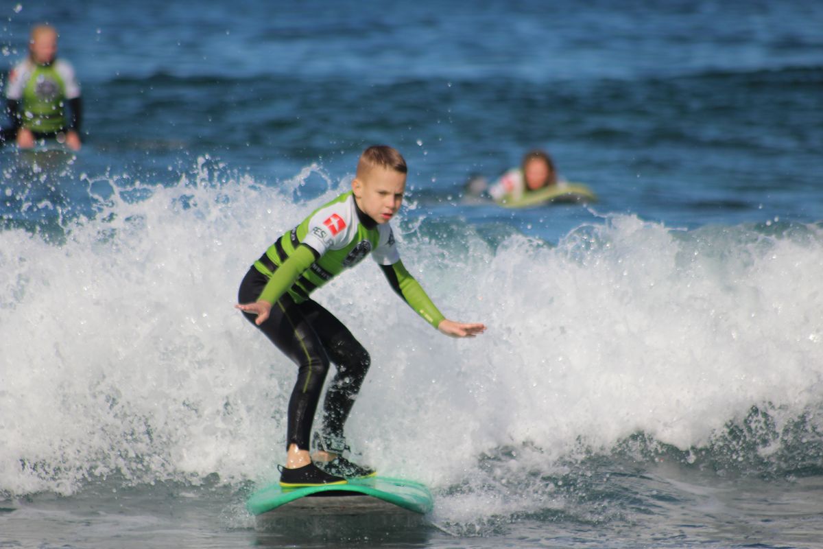 Jongen surfen op een kleine golf op Tenerife.