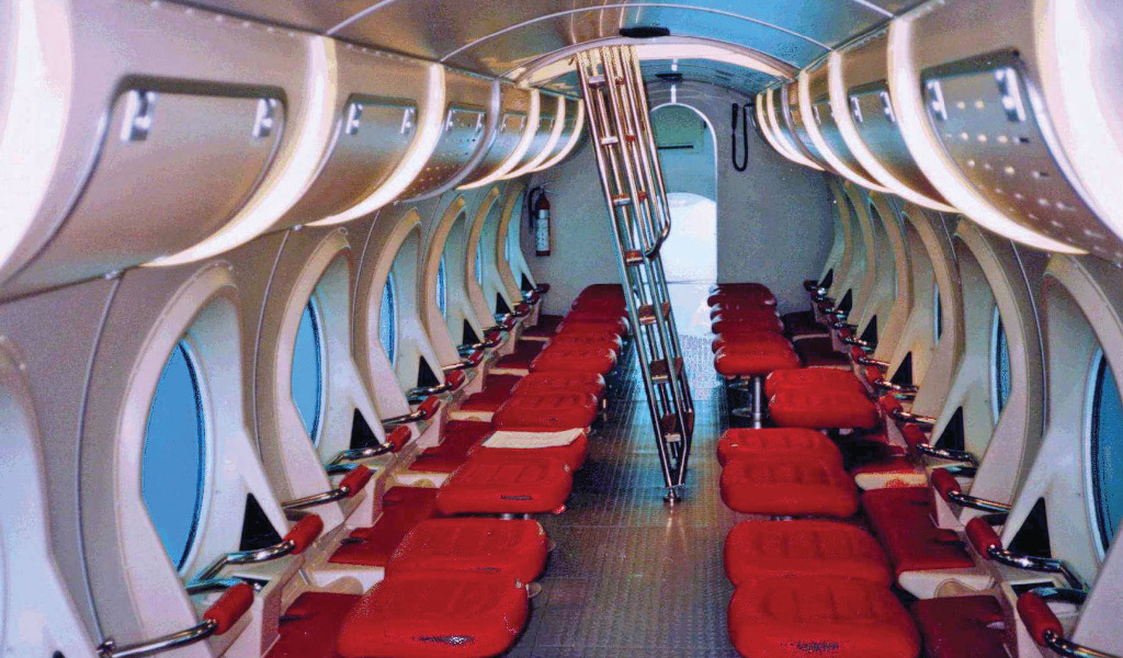 Interieur van een toeristenonderzeeër op Tenerife met rode stoelen en grote ramen.