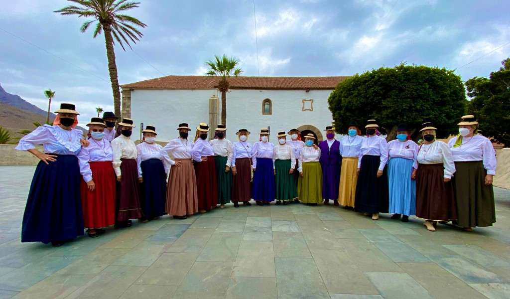 Groep mensen in traditionele kostuums in La Gomera, Tenerife, voor een gebouw.