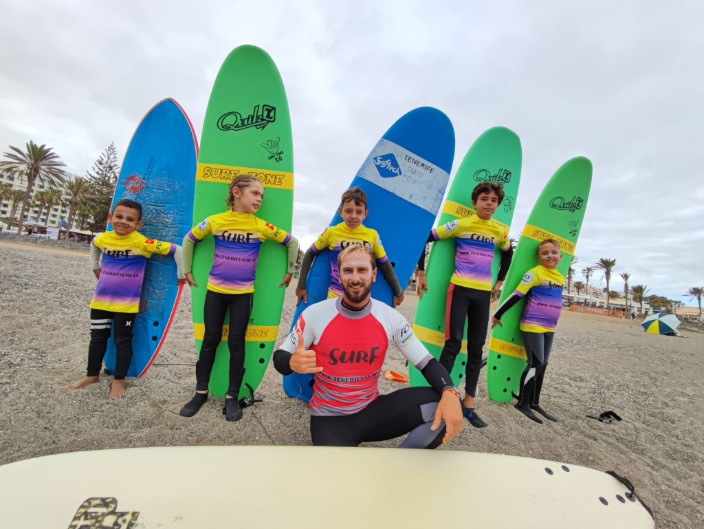 Surfinstructeur met kinderen die boards vasthouden op het strand van Tenerife.