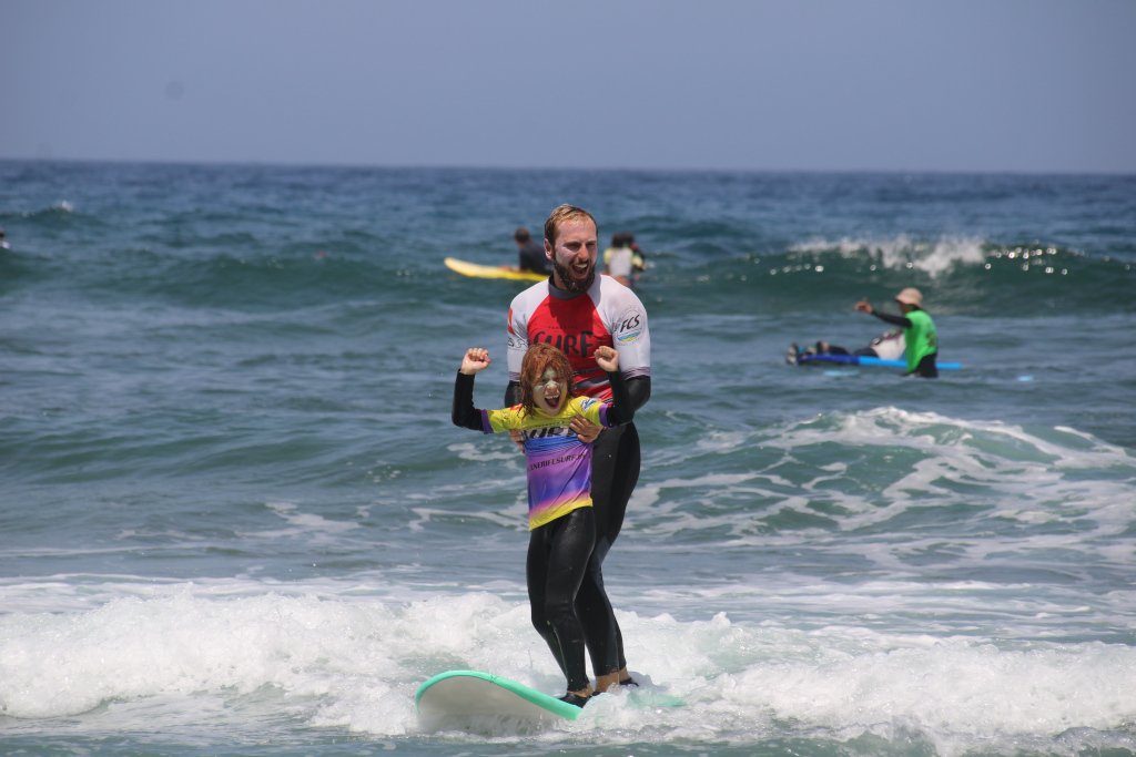 Volwassen en kindsurfer in surfles op een strand op Tenerife.