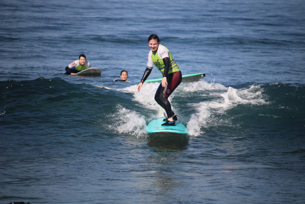 Surfer surft op een golf in Punta del Hidalgo, Tenerife, met twee mensen op de achtergrond.