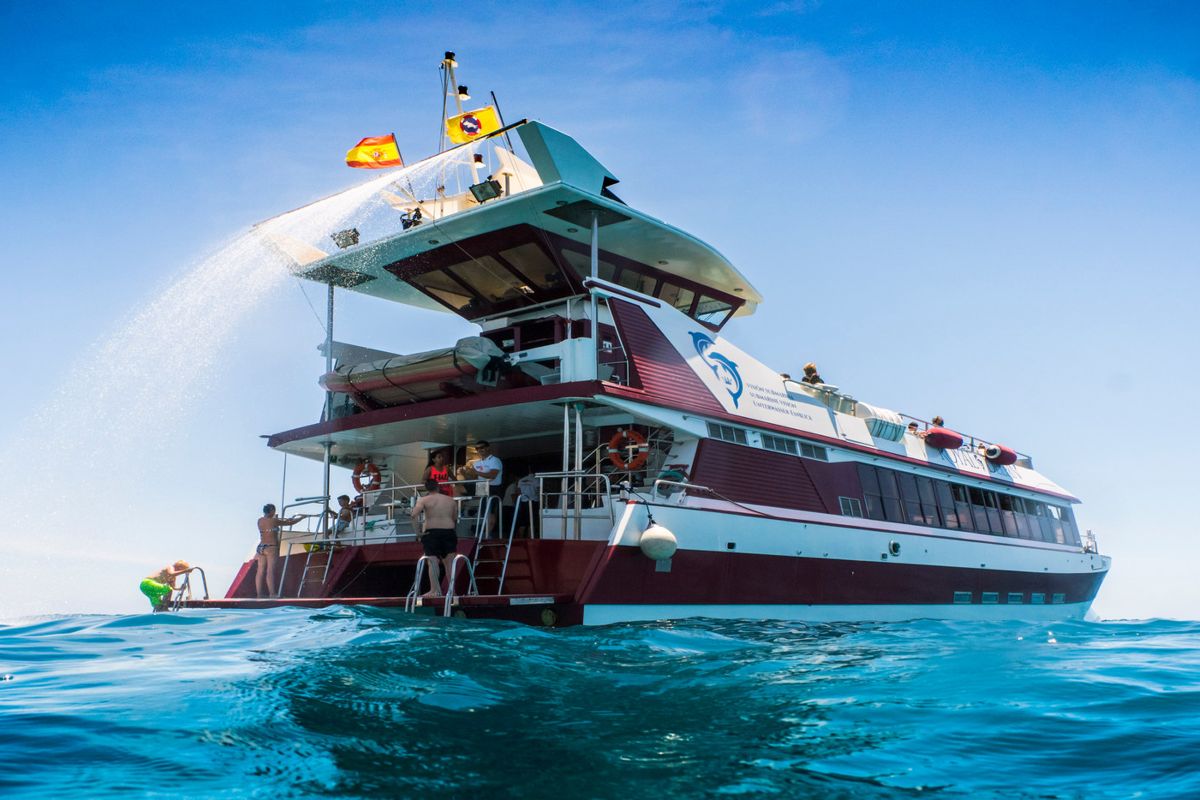 Mensen zwemmen in de zon bij een toeristenboot op Tenerife.