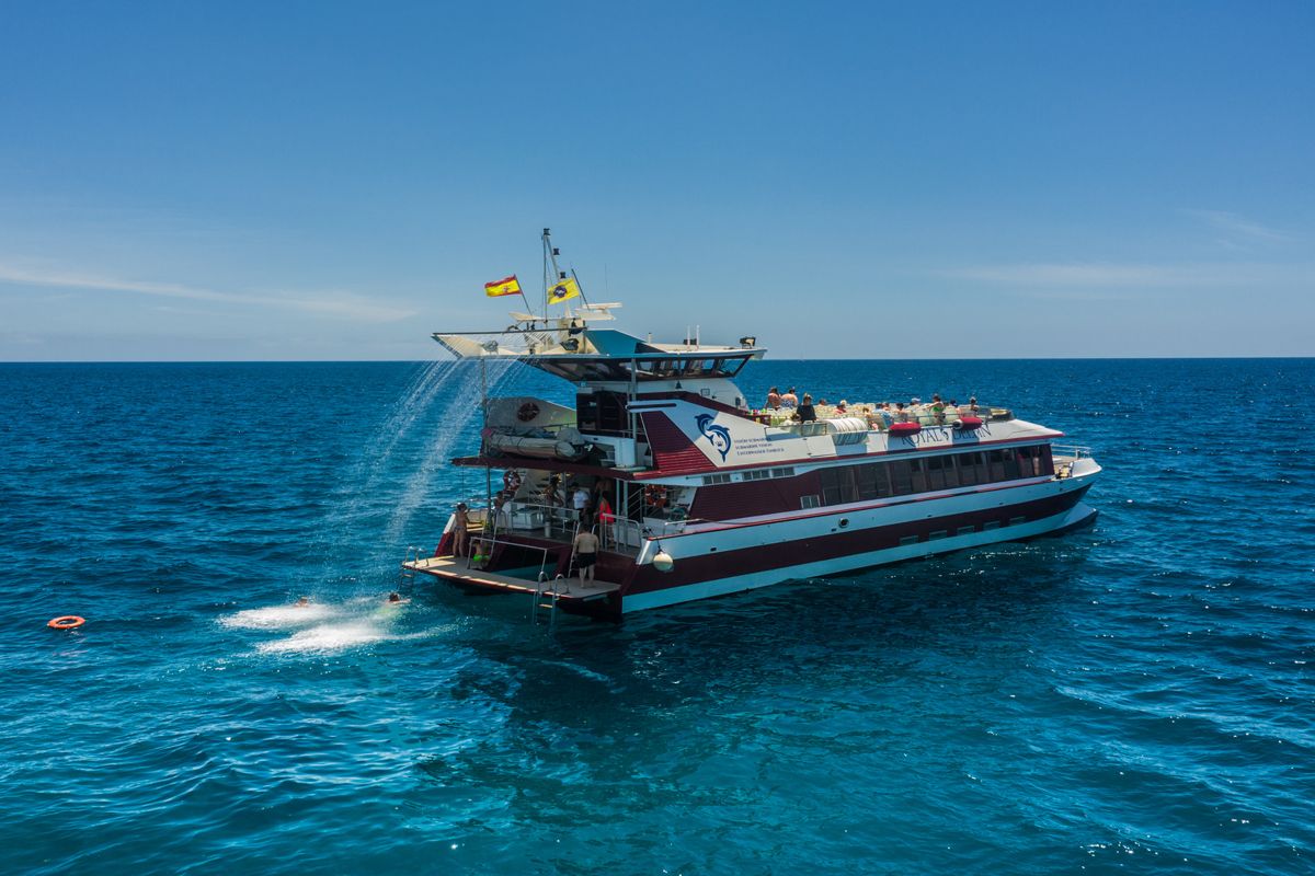 Toeristische boot op de oceaan nabij Tenerife, met passagiers en een Spaanse vlag.