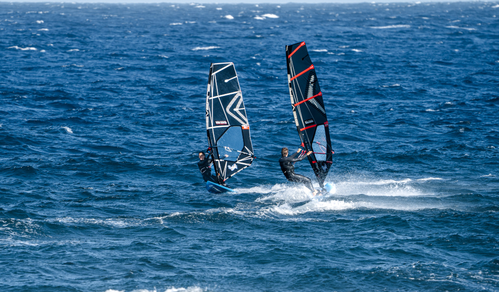Twee mensen windsurfen in de zee van El Médano, Tenerife.