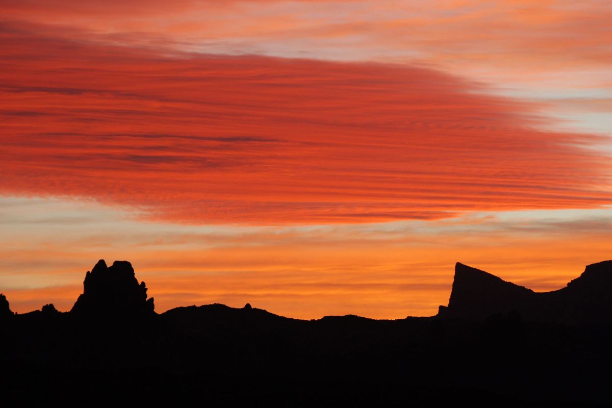 Zonsondergang boven bergen op Tenerife met rode wolken en een oranje lucht.