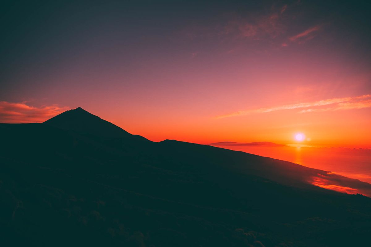 Zonsopgang boven de berg Teide op Tenerife met rode luchten en zon aan de horizon.