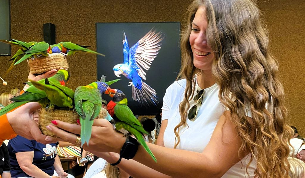 Vrouw die meerdere papegaaien vasthoudt in Loro Parque op Tenerife.