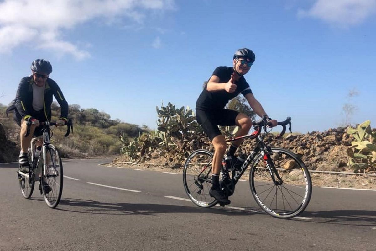 Fietsers op de weg bij cactussen op Tenerife onder heldere lucht.