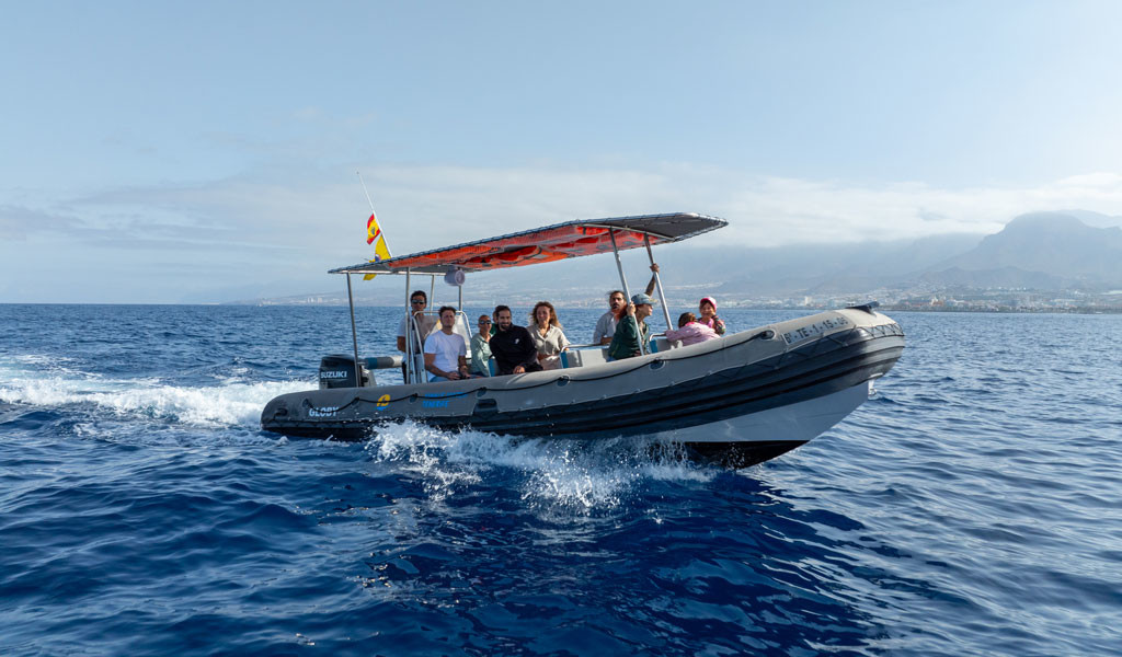 Groep mensen op een opblaasboot die langs de kust van Tenerife varen.