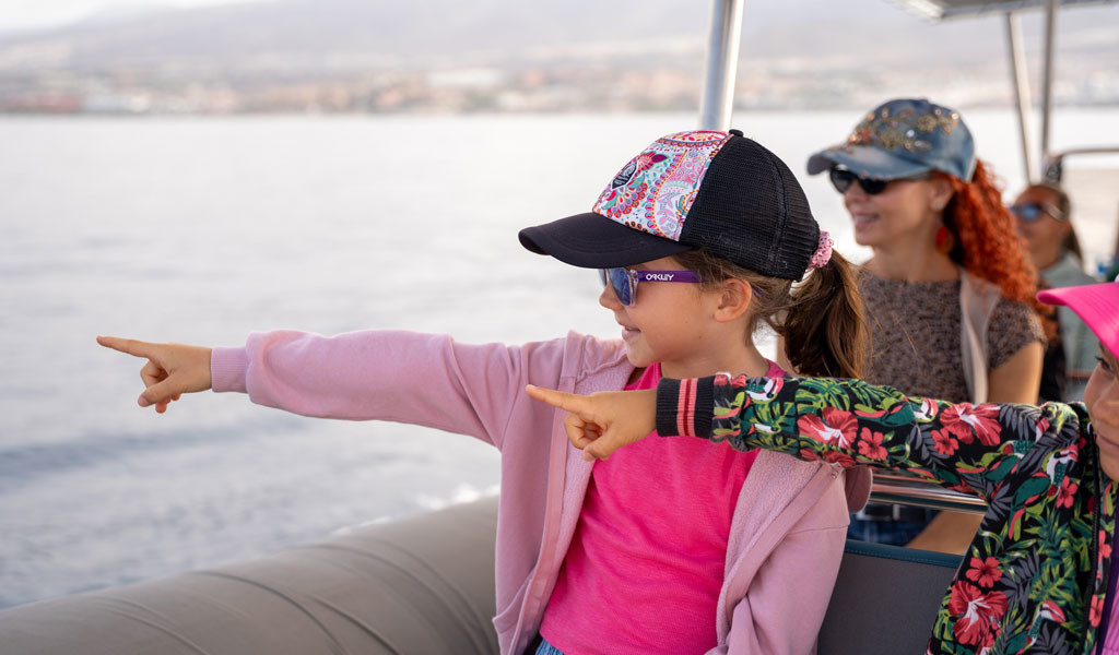 Meisjes die vanaf een boot aan de kust van Tenerife wijzen.