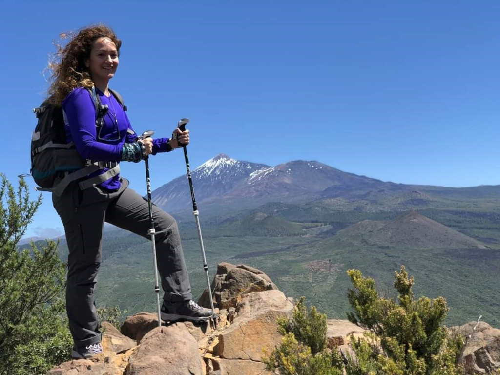 Wandelaar met stokken op een rotsachtig pad met de berg Teide op de achtergrond, Tenerife.