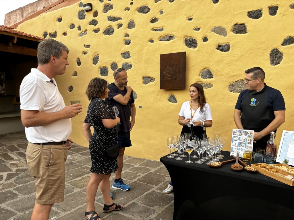 Groep mensen bij wijnproeverij op Tenerife, naast een tafel met drankjes en snacks.