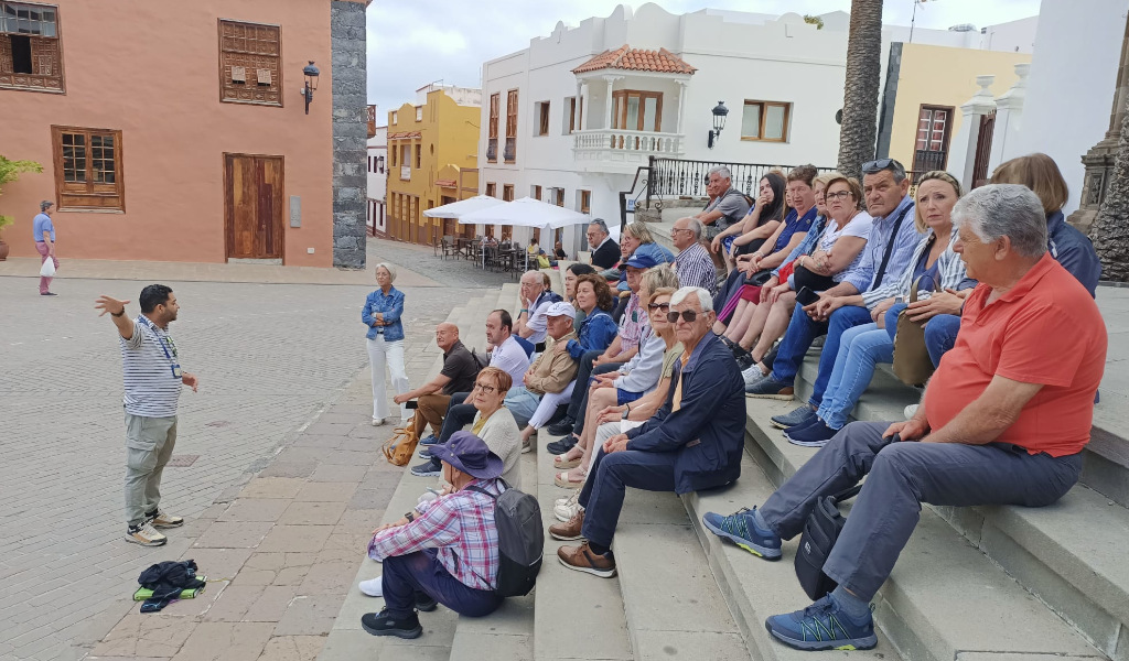 Groep toeristen op een plein in La Laguna, Tenerife, luisterend naar een gids.