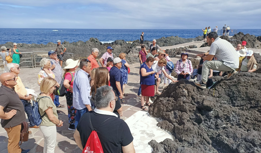 Groep mensen luistert naar een gids over vulkanische gesteenten in Puerto de la Cruz, Tenerife.