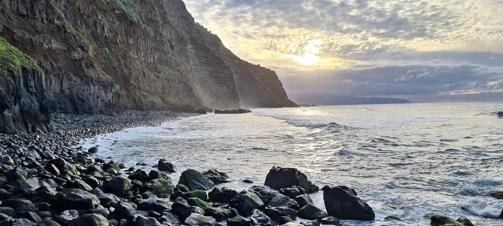 Rotsachtige kustlijn bij zonsondergang op Tenerife met kliffen en kalme zee.