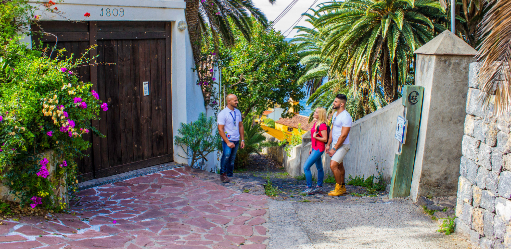 Drie mensen praten op een straat omringd door palmbomen op Tenerife.