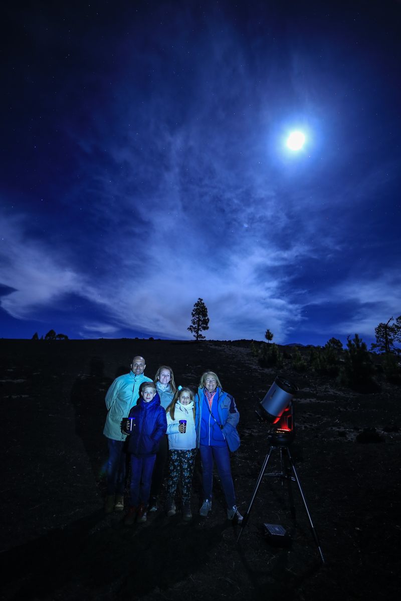 Groep mensen met telescoop die de nachtelijke hemel op Tenerife observeert.