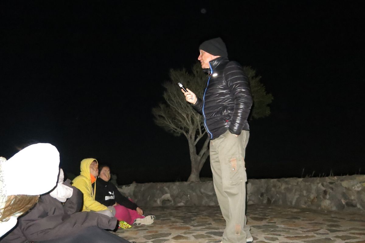 Persoon die 's nachts buiten praat op Tenerife, met een groep die in de buurt zit.