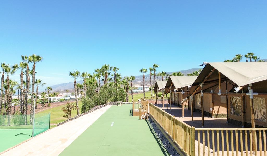 Hutten naast palmbomen en bergen in een complex op Tenerife.