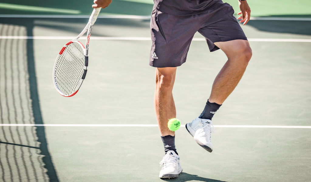 Tennisser op een baan op Tenerife, die een bal slaat met zijn racket.