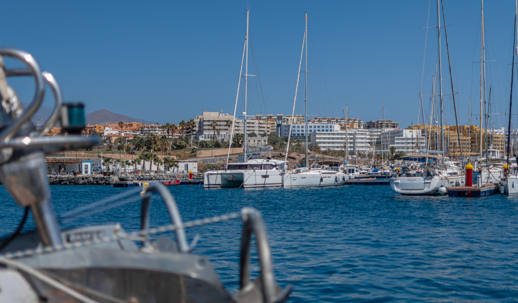 Marina in Costa Adeje, Tenerife, met jachten en gebouwen op de achtergrond.