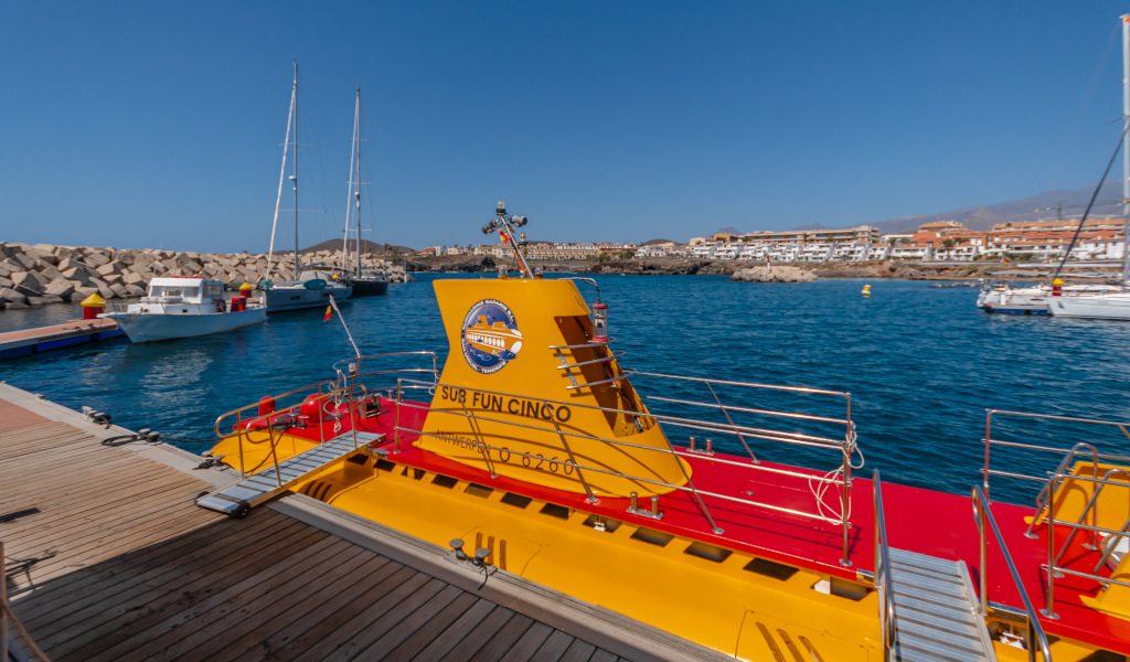 Gele onderzeeër lag aangemeerd in de haven van Puerto de la Cruz, Tenerife, met boten op de achtergrond.