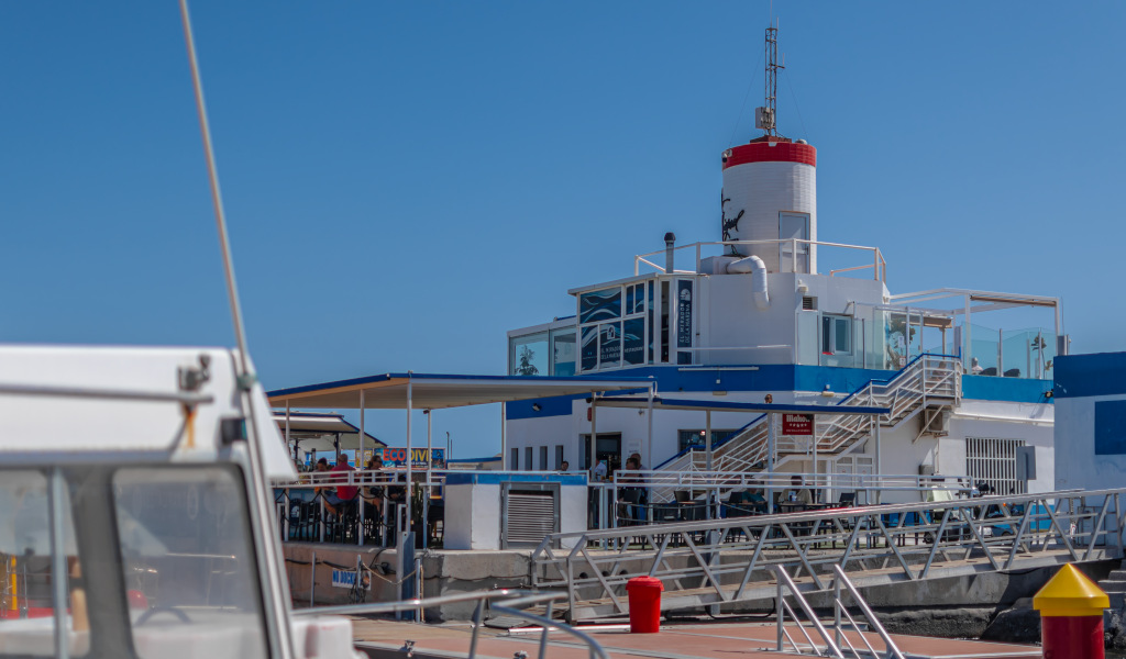 Wit en blauw gebouw met rode vuurtoren in Santa Cruz de Tenerife, gezien vanaf een pier.